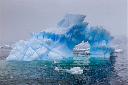 simsearch:6119-09074245,k - Blue iceberg arch in snowy weather, from sea level, Waterboat Point, Paradise Bay, Graham Land, Antarctic Peninsula, Antarctica, Polar Regions Stock Photo - Premium Royalty-Free, Code: 6119-09161636