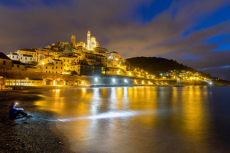 simsearch:6119-09182709,k - A tourist sitting on the beach observes the village at night, Cervo, Imperia province, Liguria, Italy, Europe Stockbilder - Premium RF Lizenzfrei, Bildnummer: 6119-09182718