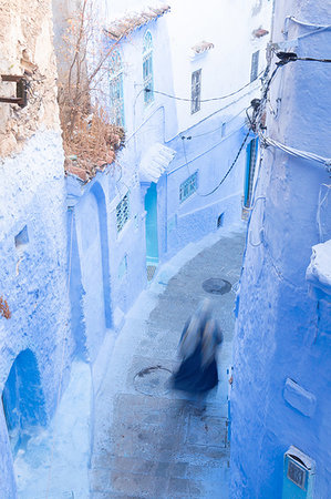 Woman in dark blue traditional clothing running down (blurred) a typical blue painted alleyway in Chefchaouen, Morocco, North Africa, Africa Stock Photo - Premium Royalty-Free, Code: 6119-09253353