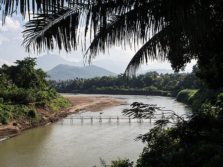 Nam Kang River with mountains, bamboo bridge, and palm trees, Luang Prabang, Laos, Indochina, Southeast Asia, Asia Stock Photo - Premium Royalty-Free, Code: 6119-09203146