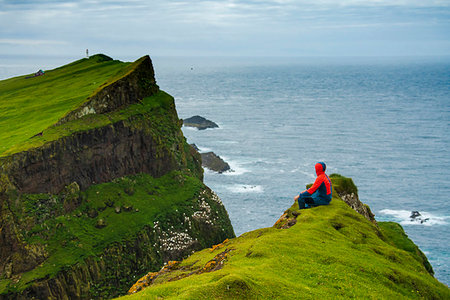 simsearch:6119-09161686,k - Man sitting on cliffs looks towards the lighthouse, Mykines island, Faroe Islands, Denmark, Europe Photographie de stock - Premium Libres de Droits, Code: 6119-09238643