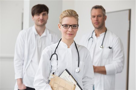 Female doctor with file while colleagues in background Photographie de stock - Premium Libres de Droits, Code: 6121-07740088
