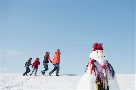 Family talking walk in winter, snowman in foreground, Bavaria, Germany Stock Photo - Premium Royalty-Free, Code: 6121-07740017