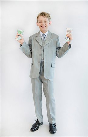 Boy holding paper money in his hand, smiling, portrait Stock Photo - Premium Royalty-Free, Code: 6121-07740518