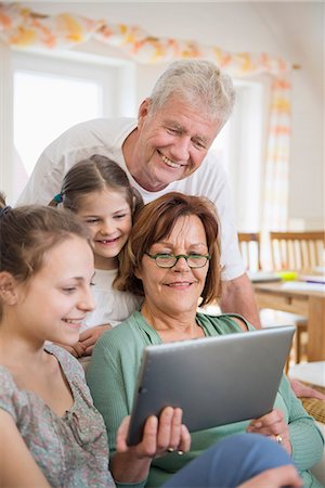 Grandparents and granddaughters looking in digital tablet, smiling Stock Photo - Premium Royalty-Free, Code: 6121-07740655
