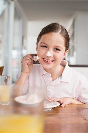 Playful girl smearing cake on her nose Stock Photo - Premium Royalty-Free, Code: 6121-07741077