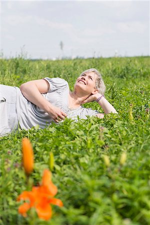 Mature woman lying in grass, smiling Stock Photo - Premium Royalty-Free, Code: 6121-07741004