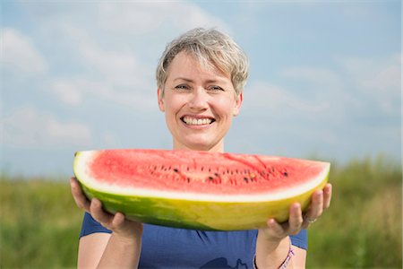 pastèque - Portrait of mature woman holding watermelon, smiling Photographie de stock - Premium Libres de Droits, Code: 6121-07741011