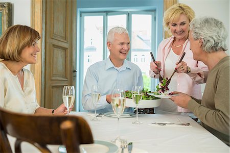 Woman serving salad to her friends, smiling Stock Photo - Premium Royalty-Free, Code: 6121-07741130