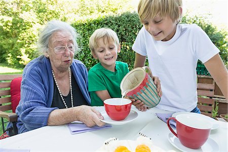 Grandson pouring milk in his grandmothers cup Photographie de stock - Premium Libres de Droits, Code: 6121-07741213