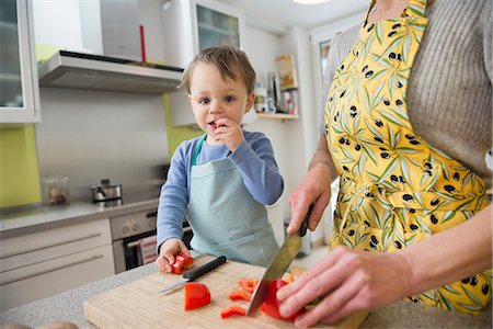 Son nibbling vegetables while mother is cutting them Foto de stock - Sin royalties Premium, Código: 6121-07741394