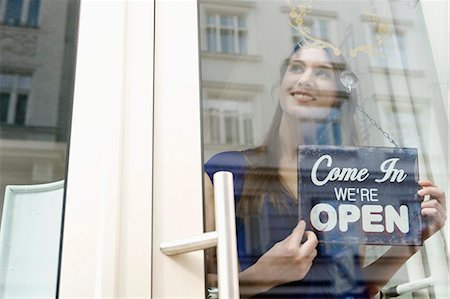 Sales girl holding opening board of fashion shop, smiling Stockbilder - Premium RF Lizenzfrei, Bildnummer: 6121-07741505