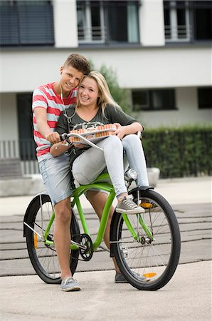 short pants (casual summer wear) - Portrait of teenage couple listening music on bicycle, smiling Stock Photo - Premium Royalty-Free, Code: 6121-07741529