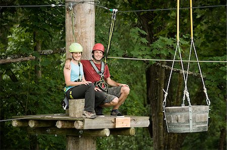 Young woman and young man sitting on stump, smiling Stock Photo - Premium Royalty-Free, Code: 6121-07741692