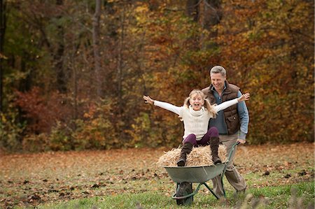 parent - Father pushing happy daughter in wheelbarrow Stock Photo - Premium Royalty-Free, Code: 6121-07741716