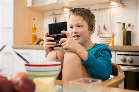 Boy playing video game in kitchen Foto de stock - Sin royalties Premium, Código: 6121-07809653