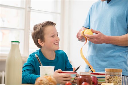pyjamas (sleepwear with pants) - Father peeling apple for son at breakfast table Stock Photo - Premium Royalty-Free, Code: 6121-07809630