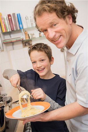 Father and son eating spaghetti in kitchen Stock Photo - Premium Royalty-Free, Code: 6121-07809791