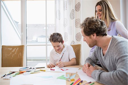 Boy drawing a picture with parents at table Photographie de stock - Premium Libres de Droits, Code: 6121-07809880