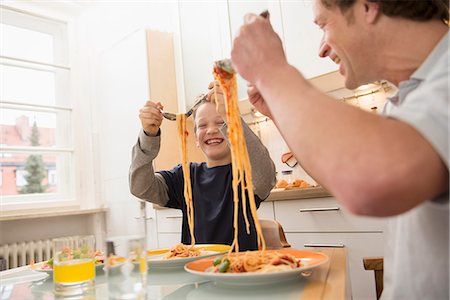 spaghetti - Father and son eating spaghetti in kitchen Stock Photo - Premium Royalty-Free, Code: 6121-07809802