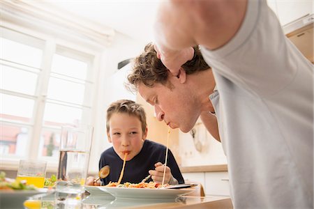 spaghetti - Father and son eating spaghetti in kitchen Stock Photo - Premium Royalty-Free, Code: 6121-07809805