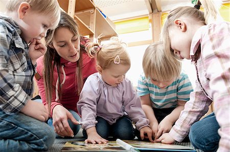 Female educator and four kids looking at picture book Photographie de stock - Premium Libres de Droits, Code: 6121-07810105