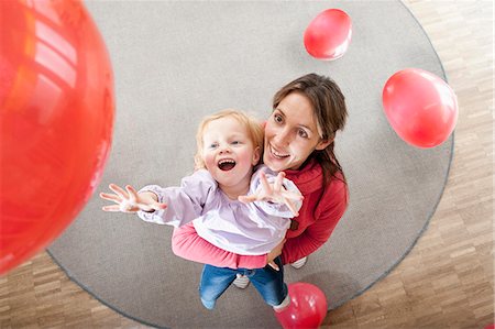 Female educator and little girl playing with red balloons in kindergarten Photographie de stock - Premium Libres de Droits, Code: 6121-07810111
