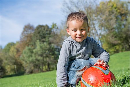 Portrait small boy red football meadow smiling Stock Photo - Premium Royalty-Free, Code: 6121-07970114