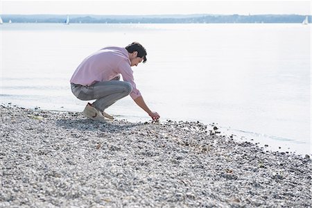 steinern - Young man gathering stones beach water Stockbilder - Premium RF Lizenzfrei, Bildnummer: 6121-07992478