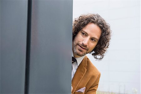Portrait man close up wall curious looking hiding Foto de stock - Sin royalties Premium, Código: 6121-07992505