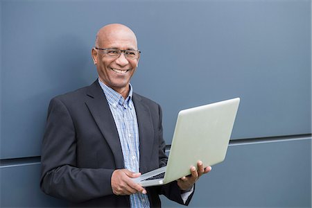 Happy African businessman holding laptop computer Foto de stock - Sin royalties Premium, Código: 6121-07992506