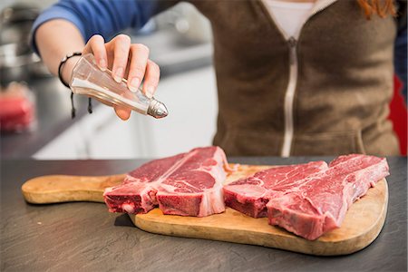 preparing food - Young Woman salting a raw steak, Munich, Bavaria, Germany Stock Photo - Premium Royalty-Free, Code: 6121-07992521