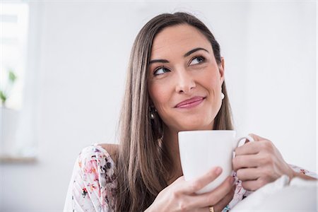 daydreaming (eyes open) - Beautiful woman drinking cup of coffee at sofa, Munich, Bavaria, Germany Stock Photo - Premium Royalty-Free, Code: 6121-07992610