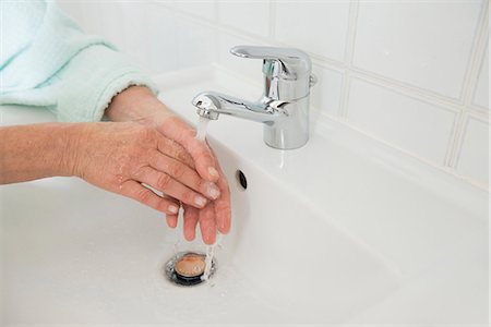 Senior woman washing hands in bathroom sink, Munich, Bavaria, Germany Stock Photo - Premium Royalty-Free, Code: 6121-08106576