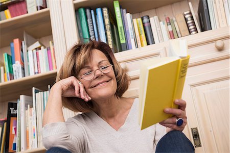 Senior woman sitting in front of bookshelf and reading, Munich, Bavaria, Germany Photographie de stock - Premium Libres de Droits, Code: 6121-08106593