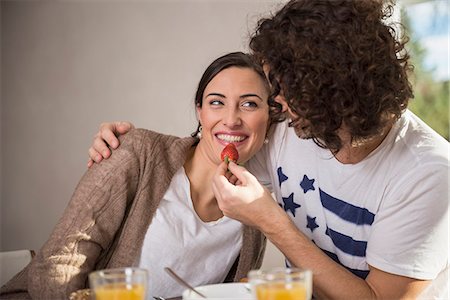 Mid adult man feeding a strawberry to his wife, Munich, Bavaria, Germany Photographie de stock - Premium Libres de Droits, Code: 6121-08106503
