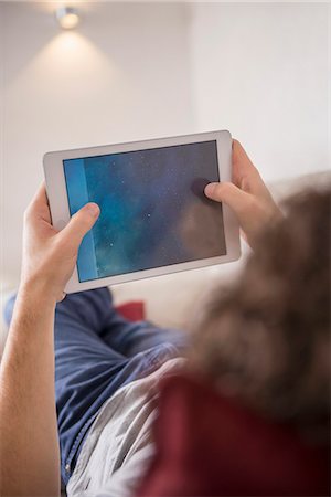 Man lying down on couch and using a digital tablet, Munich, Bavaria, Germany Foto de stock - Sin royalties Premium, Código: 6121-08106522