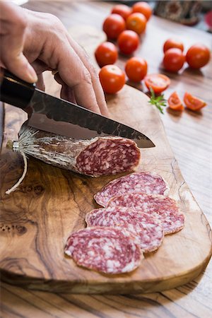 Person's hand chopping sausage with knife, Germany Photographie de stock - Premium Libres de Droits, Code: 6121-08106535