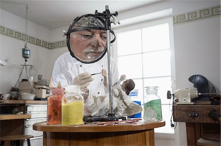 Senior sculptor colouring a Jesus Christ statue at workshop, Bavaria, Germany Stock Photo - Premium Royalty-Free, Code: 6121-08106805
