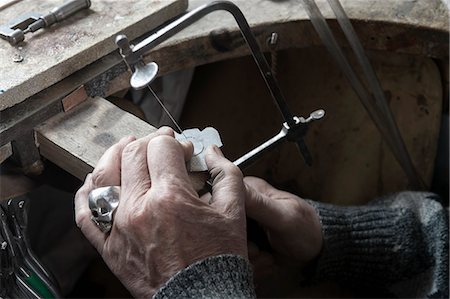 Senior goldsmith shaping crystal with hand saw in workshop, Bavaria, Germany Stock Photo - Premium Royalty-Free, Code: 6121-08106902