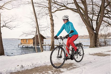 Mature woman riding bicycle on snow covered road, Bavaria, Germany Foto de stock - Sin royalties Premium, Código: 6121-08228675