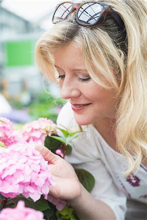 Mature woman smelling Hydrangea flowers in garden centre, Augsburg, Bavaria, Germany Stock Photo - Premium Royalty-Free, Code: 6121-08228604