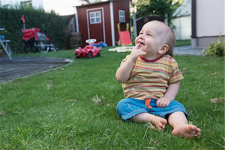 Little cute baby boy sitting on grass and laughing in a lawn, Munich, Bavaria, Germany Foto de stock - Sin royalties Premium, Código: 6121-08361540