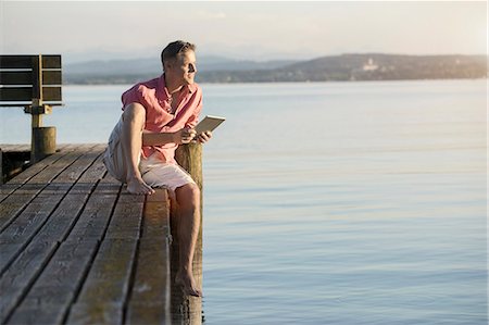 Mature man using digital tablet on pier and looking over lake, Bavaria, Germany Stockbilder - Premium RF Lizenzfrei, Bildnummer: 6121-08361565