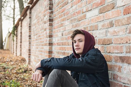 Young man sitting against brick wall and thinking, Munich, Bavaria, Germany Foto de stock - Sin royalties Premium, Código: 6121-08522173