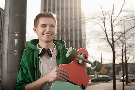 Teenager holding skateboard standing by pole and waiting for someone in street, Bavaria, Germany Foto de stock - Sin royalties Premium, Código: 6121-08522222