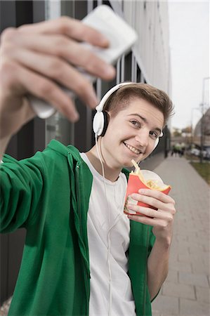 Happy teenage boy taking selfie with fries, Bavaria, Germany Photographie de stock - Premium Libres de Droits, Code: 6121-08522231