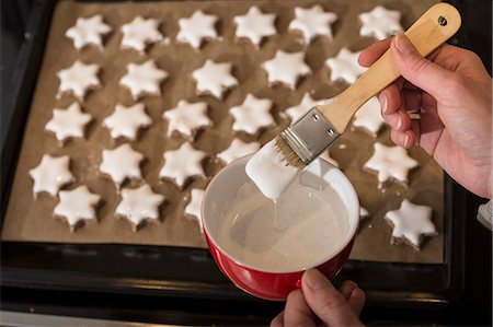 Close-up of a woman icing star shape cinnamon with basting brush, Munich, Bavaria, Germany Stockbilder - Premium RF Lizenzfrei, Bildnummer: 6121-08522342