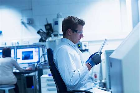 Young male scientist looking at report in an optical laboratory, Freiburg Im Breisgau, Baden-Württemberg, Germany Stockbilder - Premium RF Lizenzfrei, Bildnummer: 6121-08522450