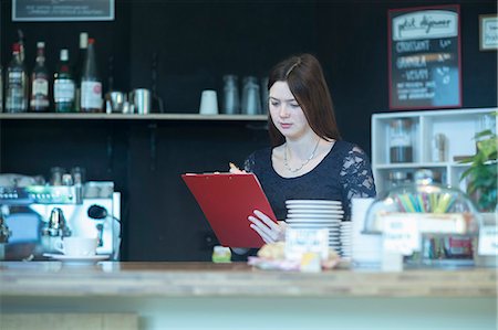 porte-blocs - Young woman checking checklist in coffee shop, Freiburg Im Breisgau, Baden-Württemberg, Germany Photographie de stock - Premium Libres de Droits, Code: 6121-08522430